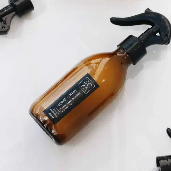 Frasco de spray de ambiente Soya em vidro âmbar, com aromatizador de tecidos, tombado sobre a bancada.