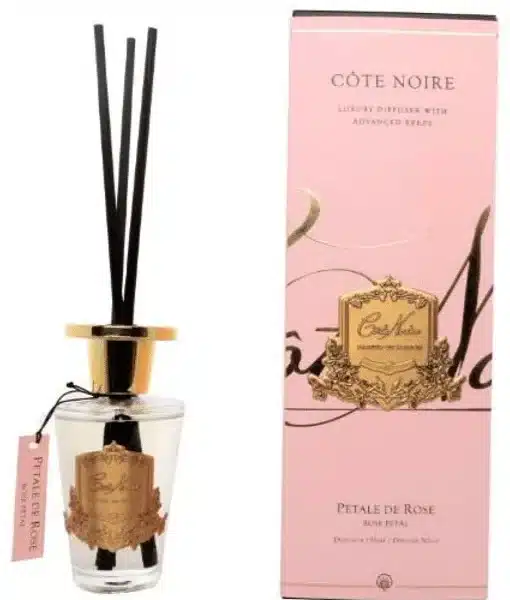 Difusor de aromas Côte Noire com varetas pretas, tampa dourada e caixa em tom rosa, aroma pétala de rosa.